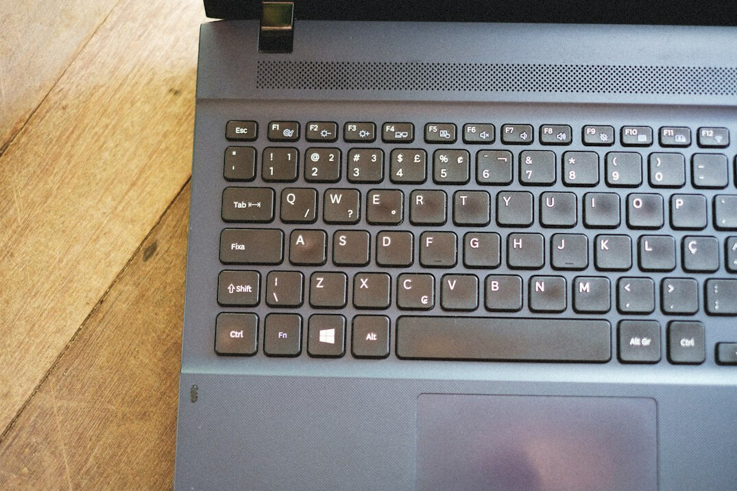 Ruke tipkaju na tipkovnici laptopa s prikazanim programskim kodom